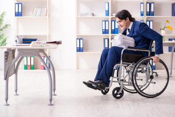 Young male employee in wheelchair working in the office 