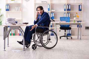 Young male employee in wheelchair working in the office 