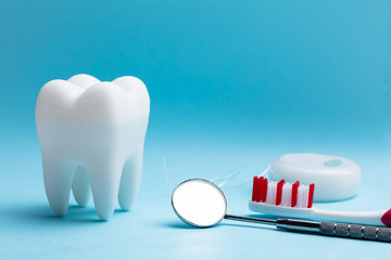 Fototapeta na wymiar Artificial Tooth And Dental Equipment On Blue Background