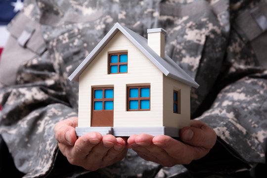 Solider Holding Model House In Hand