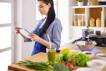 Young woman using a tablet computer to cook in her kitchen