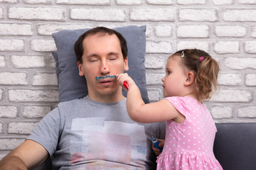 Girl Painting Father's Face With Color Tube