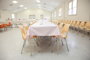 long table with white tablecloth and yellow chairs in a large fire hall or legion