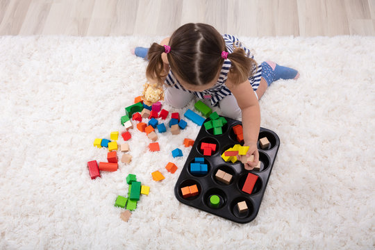 Girl Sitting On Carpet Playing With Colorful Blocks