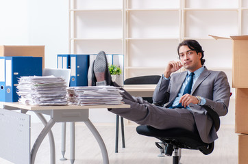 Young man employee with boxes in the office 