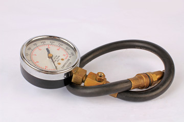 Closeup of compression tester with rubber extension tube for single cylinder motorcycle.