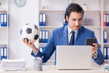 Young handsome businessman with soccer ball in the office 