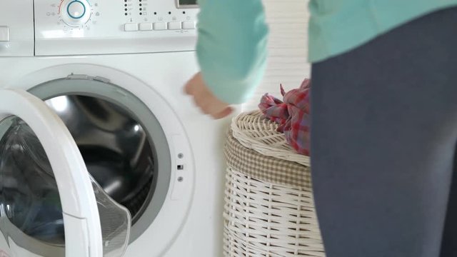 Woman loads laundry in the washing machine before washing