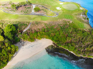Aerial view luxury golf field next the cliff, ocean and beach in Bali island, Indonesia.  Aerial view of footpath on golf course.