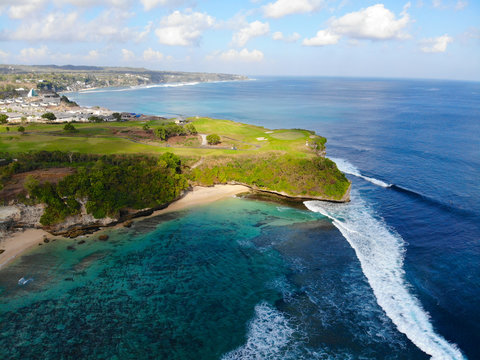 Aerial view luxury golf field next the cliff, ocean and beach in Bali island, Indonesia.  Aerial view of footpath on golf course.