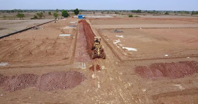 drone shot of a road grader working on the construction site 