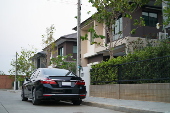 black modern car parked on road of village house
