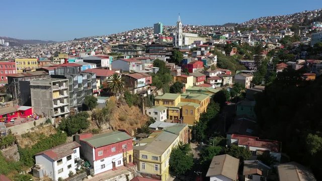 Aerial drone view of Colourfully decorated houses on the hills of the historic port city. Iglesia de los Doce Apostoles church on the background. Valparaiso, Chile