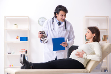 Obraz premium Old pregnant woman visiting young male doctor 