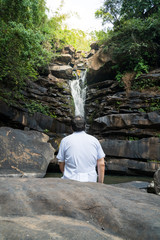 Man with white shirt saw the secret waterfall with sunlight in Thailand