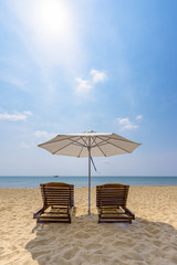 Wooden sunbeds and umbrella on the golden sand of a paradise beach