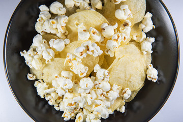 Potato chips and Popcorn in a plate on white background