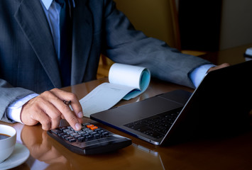 Businessman write cheque, work on laptop computer at office.
