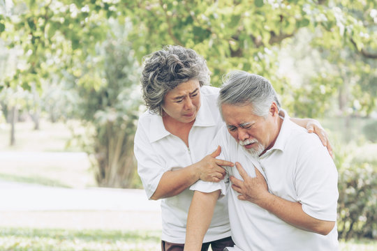 Senior Male Asian Suffering From Bad Pain In His Chest Heart Attack At Garden Park , Wife Supporting Husband - Elderly Couple Senior Heart Disease