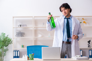 Young male doctor drinking in the office 