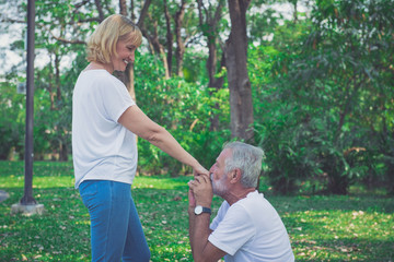 Happy old man kiss his wife hand at the park