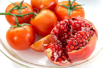 a group tomatoes and pomegranate on white table background
