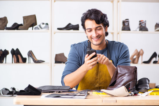 Young man repairing shoes in workshop 