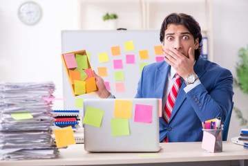 Young male handsome employee in conflicting priorities concept 