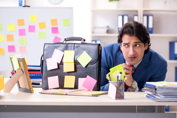 Young male handsome employee in conflicting priorities concept 