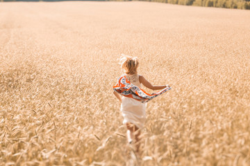 Blonde girl model on a wheat field. Young woman enjoying nature. Beautiful girl running in the rays of sunlight. Sunlight.