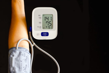 Woman take care for health,using sphygmomanometer to measure blood pressure,pulse and heart rate by self,isolated on dark background. Healthcare and hypertension concept.