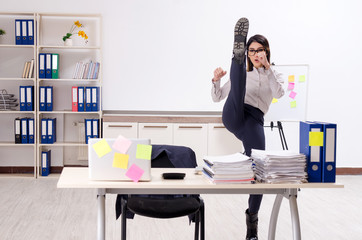 Young female employee doing exercises at workplace 