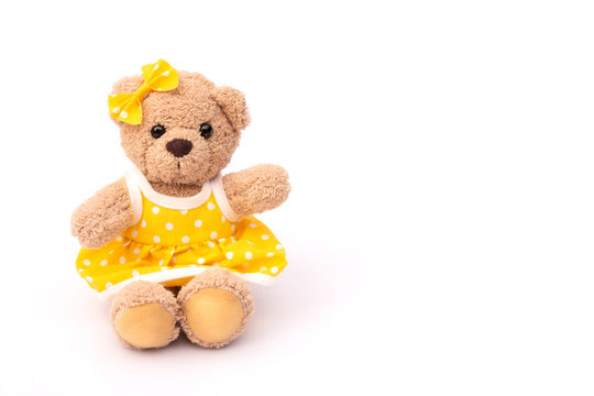 Brown teddy bear in yellow skirt isolated on white background.
