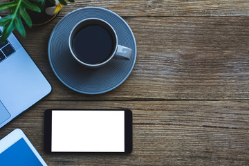 Mockup mobile smart phone with blank screen  ,cup of coffee and laptop computer on old wooden table background.