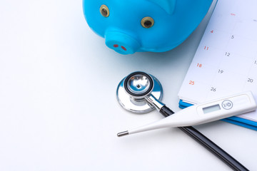 Medical stethoscope, blue piggy bank,calendar and thermometer isolated on white background. Saving...