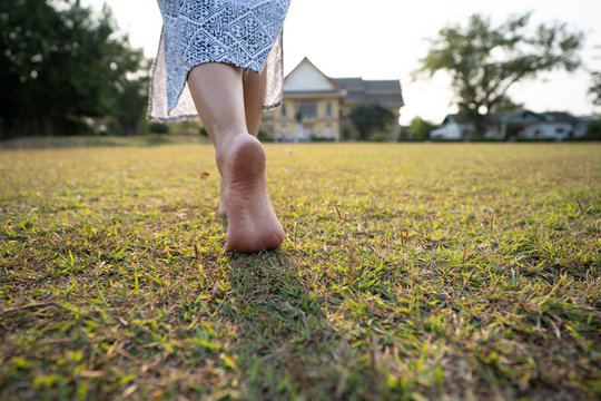 woman barefoot walking on the grass ground with sunset light