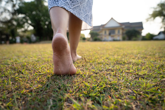 woman barefoot walking on the grass ground with sunset light