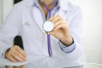 Doctor woman holds stethoscope head, close-up of hands. Physician ready to examine and help patient. Helping and insurance in health care, best treatment and medicine concept