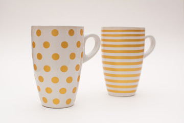 Two cups of coffee stand together. Cups for coffee with a pattern in the form of circles and stripes on a white background. Layout, copy space.