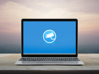 cctv camera flat icon with modern laptop computer on wooden table over office city tower and skyscraper at sunset sky, vintage style, Business security and safety online concept