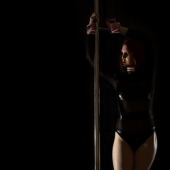 beautiful redhead woman in lingerie dancing near the pilon with handcuffs. exotic pole dance