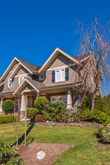 Beautiful exterior of newly built luxury home. Yard with green grass and walkway lead to ornately designed covered porch and front entrance.