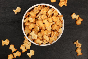 Goldfish crackers in a bowl, shot from above on a black background with copy space