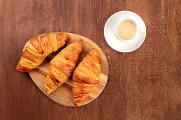 A French breakfast with croissants and coffee, shot from the top on a dark rustic wooden background with a place for text