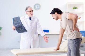 Obraz premium Young man visiting old male doctor radiologist 