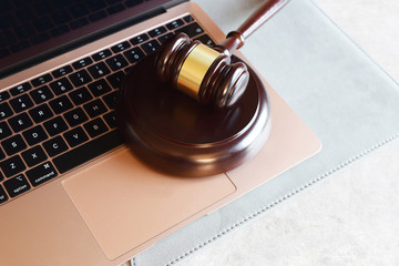 Judge gavel on rose gold color laptop computer. Concept of online auction, cyber crime, law system.