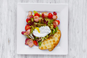 Warm vegetable salad with bacon and poached egg