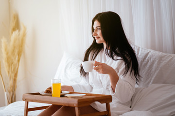 Obraz na płótnie Canvas woman having breakfast in bed in cozy hotel room