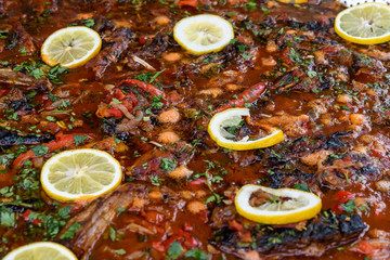 Close up of a large portion of fish sour soup known as borscht with tomatoes, decorated with lemon slices, traditional East European food