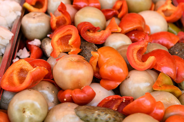 Mixed pickles on a table at a food market with pickled cucumbers green tomatoes and red peppers